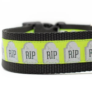 May include: A black dog collar with a lime green ribbon featuring a repeating pattern of gray tombstones with the text "RIP" on them.