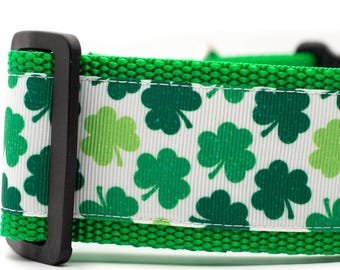 May include: Green dog collar with a white band patterned with green shamrocks. The collar has a black buckle and green woven trim. A festive accessory for pets.