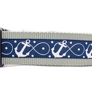 May include: A gray dog collar with a navy blue and white anchor pattern. The collar has a black buckle.