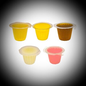 May include: Five small, individual cups of jelly desserts in various colours: yellow, light yellow, brown, and pink. Each cup is sealed with a clear plastic lid. The cups are arranged against a gradient background.