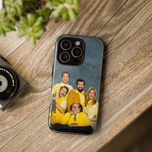 May include: A phone case featuring a group of people in yellow shirts. The case has a blue background and a black camera bump with three lenses.