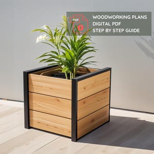 May include: A square wooden planter with a black metal frame, containing a green plant with white flowers. The planter has three horizontal wooden panels. Text on the image reads: WOODWORKING PLANS DIGITAL PDF STEP BY STEP GUIDE.