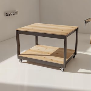 Könnte beinhalten: Eine helle Werkbank aus Holz mit einem dunkelgrauen Metallrahmen und einem unteren Regal. Die Werkbank steht auf Rollen. Im Hintergrund befindet sich eine zweite Werkbank aus Holz.