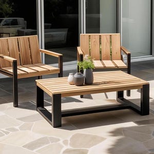 Könnte beinhalten: Ein hölzerner Outdoor-Couchtisch mit schwarzem Metallrahmen, dazu zwei passende Stühle mit Holzlatten und schwarzen Metallrahmen. Die Stühle und der Tisch stehen auf einer Steinterrasse.