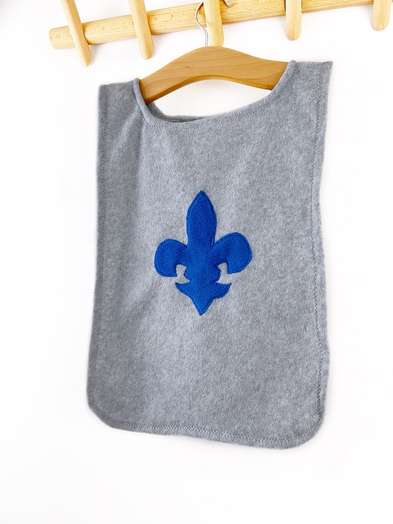 May include: A gray fleece cape with a blue embroidered fleur-de-lis design.