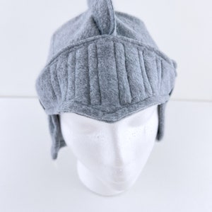 May include: Gray felt knight helmet hat with a pointed top and a visor. The hat is on a white mannequin head.