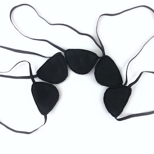 May include: Five black eye patches with elastic straps. The eye patches are arranged in a semi-circle.