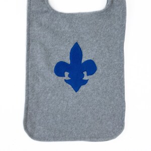 May include: Gray fleece fabric with a blue embroidered fleur-de-lis.