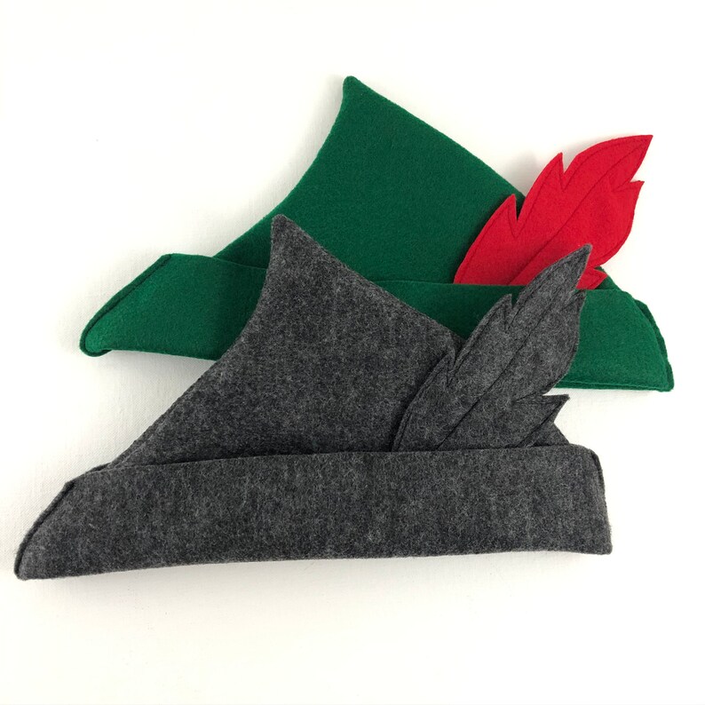 May include: Two felt hats with feathers. The top hat is green with a red feather. The bottom hat is gray with a black feather.