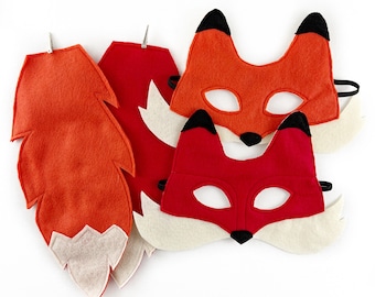 May include: Two felt fox masks with black eyes and noses, one orange and one red, and a matching orange felt fox tail with white fur trim.