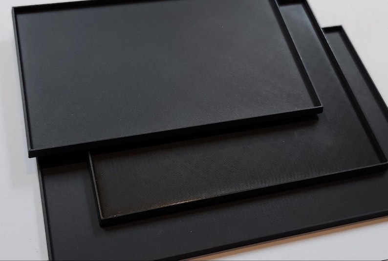 May include: Three black rectangular baking trays stacked on top of each other.