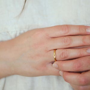 May include: A gold ring with a small letter 'J' engraved on the band.