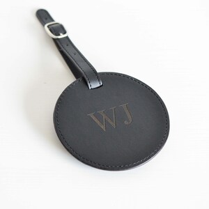 May include: Black leather luggage tag with a silver buckle and the initials "WJ" embossed in the center.