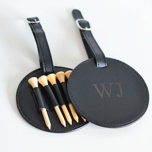 May include: Black leather golf ball holder with a loop for attaching to a bag. The holder has five wooden golf tees and is personalized with the initials "WJ".
