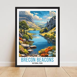 Könnte beinhalten: Ein gerahmter Kunstdruck mit einer Landschaft des Brecon Beacons Nationalparks. Das Kunstwerk zeigt einen Fluss, der durch ein Tal fließt, mit Bergen, Bäumen und bunten Blumen. Der Text "BRECON BEACONS NATIONAL PARK" steht unten.