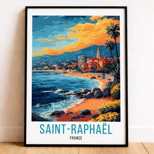 May include: A framed art print of Saint-Raphaël, France, featuring a coastal scene with a beach, buildings, and palm trees. The artwork has a vibrant color palette of blues, oranges, and greens. The text "SAINT-RAPHAËL FRANCE" is at the bottom.