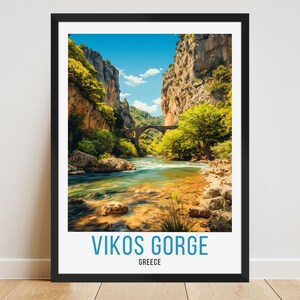 May include: Framed print of Vikos Gorge in Greece. The image features a river flowing through a canyon with a stone bridge. The sky is blue with clouds, and the landscape is filled with green trees and brown rock formations. The text "VIKOS GORGE GREECE" is at the bottom.