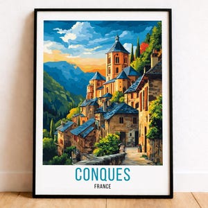 May include: Framed art print of Conques, France, featuring a colorful illustration of a village nestled in a valley. The artwork showcases buildings with blue rooftops, a tall church, and lush green hills under a vibrant sky. The text "CONQUES FRANCE" is at the bottom.