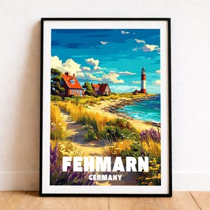 Puede incluir: Impresión artística enmarcada de Fehmarn, Alemania. La obra representa una escena costera con un faro, casas y un camino hacia la playa. El cielo es azul con nubes y el texto "Fehmarn Germany" está en la parte inferior.