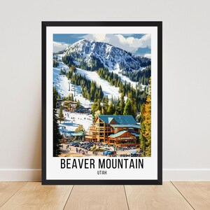 Op de afbeelding: Een ingelijste print van Beaver Mountain in Utah. Het kunstwerk toont een besneeuwde berg met skipistes, groenblijvende bomen en een lodge. De print heeft een zwart frame en de woorden "BEAVER MOUNTAIN UTAH" aan de onderkant.