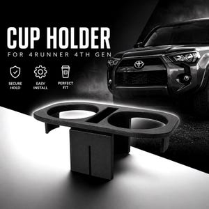 Op de afbeelding: Een zwarte dubbele bekerhouder van kunststof, ontworpen voor een 4Runner 4th Gen voertuig. Het accessoire heeft twee ronde openingen en een centrale steunstructuur. De tekst op de afbeelding luidt: CUP HOLDER FOR 4RUNNER 4TH GEN, SECURE HOLD, EASY INSTALL, PERFECT FIT.