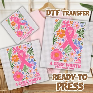 May include: Three DTF transfer sheets featuring a pink awareness ribbon surrounded by colorful floral and leaf illustrations on a grid background. The text A CURE WORTH FIGHTING FOR is printed in pink at the bottom of each design.