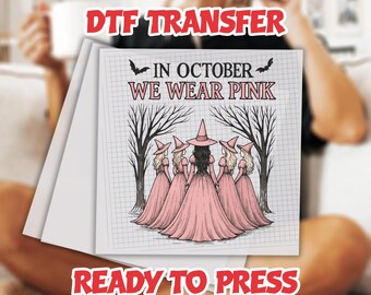 May include: DTF transfer sheet with the text "IN OCTOBER WE WEAR PINK" and an illustration of five witches in pink dresses and hats. The words "READY TO PRESS" are also visible.