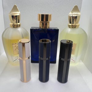 May include: Three perfume bottles with gold caps and a gold and white label. Two smaller perfume bottles with gold and black caps and a gold and white label.