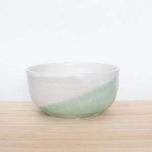 May include: A white ceramic bowl with a light green glaze on the bottom half.