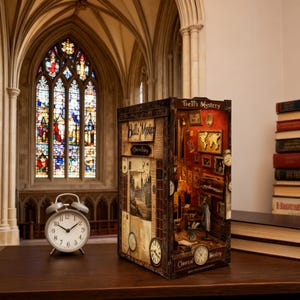 May include: A detailed diorama titled "Bell's Mystery" with a vintage aesthetic. The miniature scene features a room with clocks, maps, and framed pictures. An analog alarm clock sits in front of the diorama. The background includes a stained-glass window and a stack of books.