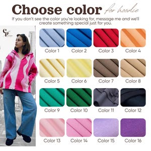 May include: The image displays a variety of hoodie color options, including blue, red, and orange. The text "Choose color for hoodie" is at the top. A person is wearing a pink and white striped hoodie and blue jeans. Sixteen color swatches are shown.