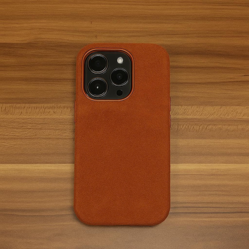 May include: A brown suede phone case for an iPhone with a camera bump and three lenses.