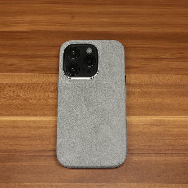 May include: A silver phone case with a textured surface. The case has a camera lens cutout with three black circles.