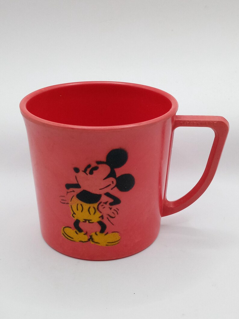 May include: A red plastic cup with a black and yellow image of Mickey Mouse.