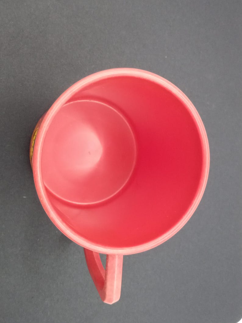 May include: A red plastic mug with a handle. The mug is empty and has a smooth surface.