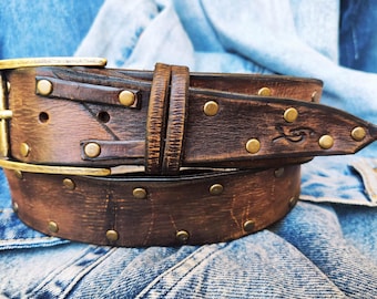 Brown leather belt with two shades of brown two pieces on the front and storage for guitar pick with bronze studs around the belt