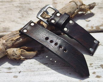 May include: Two dark brown leather watch straps with silver metal buckles and rivets. The straps are worn and have a distressed look.