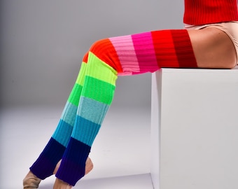 May include: Thigh-high leg warmers featuring a vibrant horizontal striped pattern in shades of red, pink, orange, lime green, light blue, and dark blue. These ribbed knit leg warmers have an open heel design and extend from the upper thigh down.