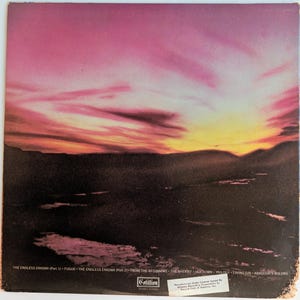 May include: Album cover featuring a vibrant sunset over a dark landscape. The sky transitions from pink to yellow, with the album title and track names listed at the bottom. The Cotillion logo is also visible.