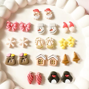 Könnte beinhalten: Ein weißes Tablett mit gewelltem Rand zeigt eine Auswahl an Miniatur-Weihnachtsschmuck. Die Ornamente umfassen Weihnachtsmann-Gesichter, Schneemänner, Schleifen, Schneeflocken, Geschenktüten, Häuser, Glocken, Tannenzapfen und Pinguine. Die Ornamente sind in verschiedenen Farben.