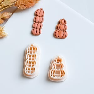 Può includere: Quattro taglierini in argilla polimerica a forma di zucca e due zucche in argilla finite in tonalità arancioni. I taglierini sono bianchi con una forma di zucca ritagliata. Le zucche finite sono impilate in due diversi design.