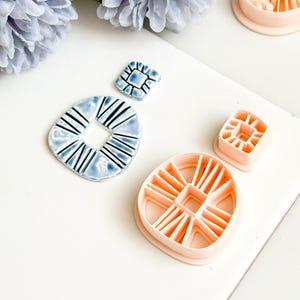 May include: A collection of ceramic and polymer clay cutters in various shapes. The ceramic pieces are blue with black lines, while the polymer clay cutters are peach-colored. The shapes include squares and rounded shapes with geometric designs.
