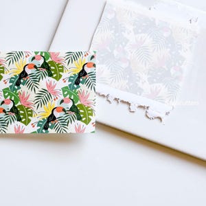 May include: A sheet of white paper with a tropical toucan and leaf pattern printed on it. The paper has been torn around the edges.