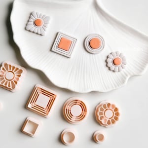 Könnte beinhalten: Ein Set mit 10 rosafarbenen Plastik-Ausstechern in verschiedenen Formen, darunter Kreise, Quadrate und Blumen. Die Ausstecher sind auf einer weißen Oberfläche angeordnet.