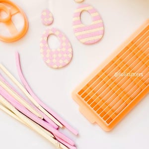 May include: A set of pink and white patterned polymer clay earrings, a pink and white patterned polymer clay circle, a set of pink and white polymer clay sticks, and a pink plastic mould with a grid pattern. The mould is labelled "@lulicutters".
