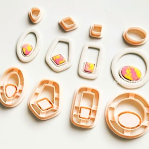 May include: A set of 10 plastic cookie cutters in various geometric shapes, including circles, ovals, squares, and rectangles. The cutters are a light peach color.