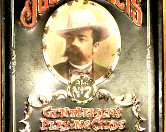 May include: A vintage Jack Daniel's playing card tin. The black tin features the brand name in red, a portrait of a man in a hat, and the text "Gentlemen's Playing Cards". The tin has a distressed, aged appearance.