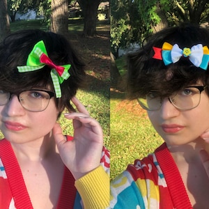 Pu&ograve; includere: Due immagini di una persona con occhiali e un cardigan colorato. La prima immagine mostra un fermaglio per capelli con fiocco verde e rosso. La seconda immagine mostra un fermaglio per capelli con fiocco con nastri gialli, blu e bianchi. Lo sfondo &egrave; un'area erbosa con alberi.