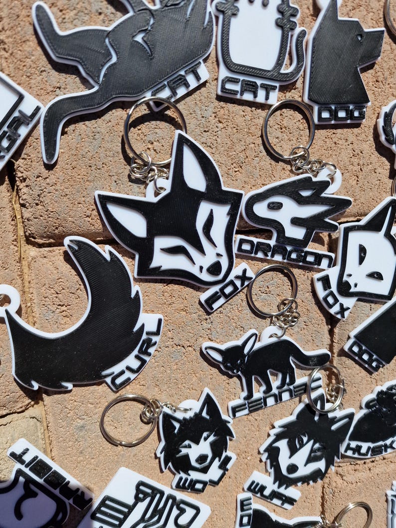black and white keychains that represent species, there are many to choose from and all are connected to a silver metal keyring clip.