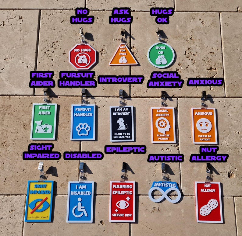 May include: A collection of colorful, rectangular and shaped tags with various text and symbols. The tags include phrases like "No Hugs", "First Aider", "Disabled", and "Nut Allergy". The tags are designed to communicate needs.